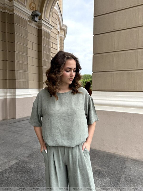 Woman in a light green outfit standing in front of a building