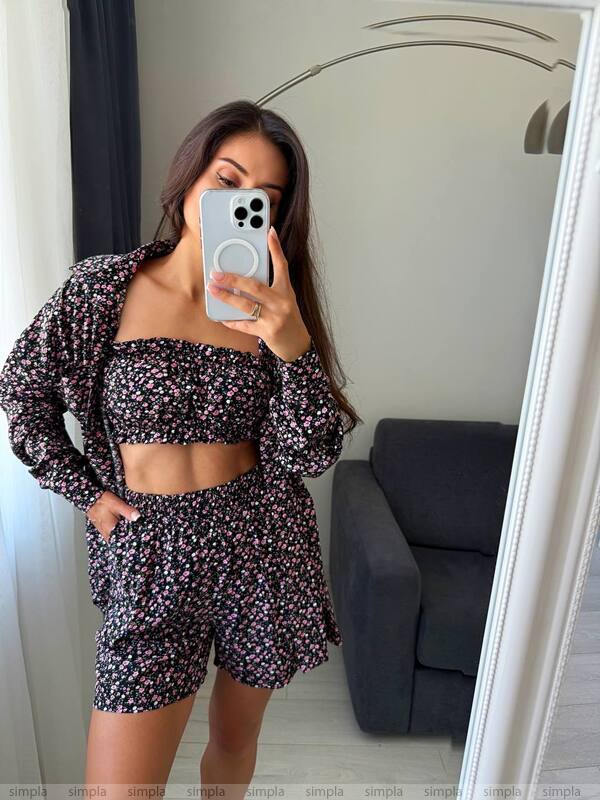 Woman taking a mirror selfie wearing a floral outfit in a room with a gray couch.