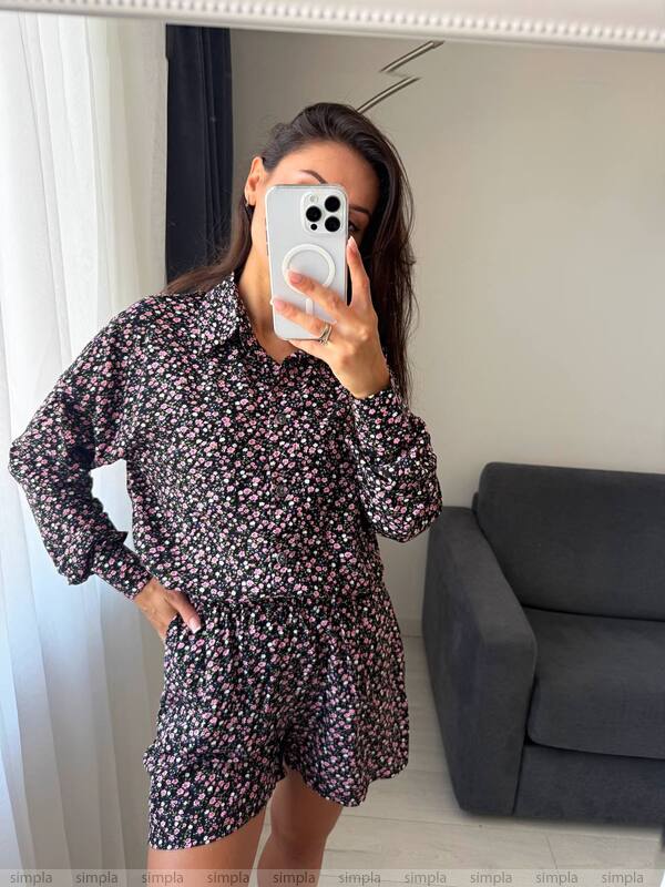 Person wearing a floral dress taking a mirror selfie in a room with a gray sofa.