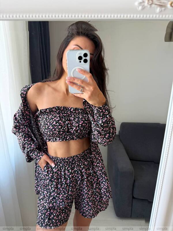 Person wearing a floral outfit taking a mirror selfie.