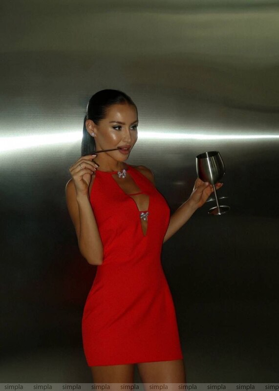 Woman in a red dress holding a glass against a dark background