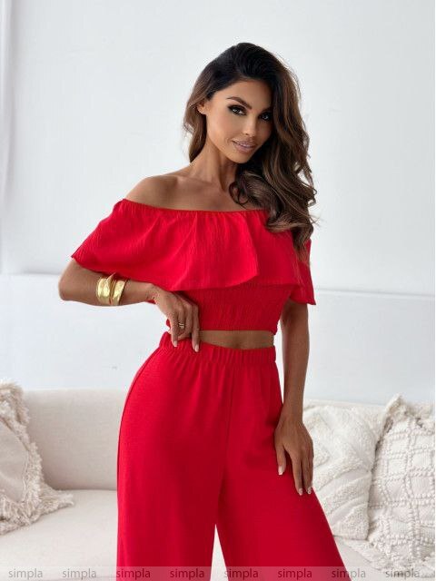 Woman wearing a red outfit with ruffled sleeves in a minimalistic setting