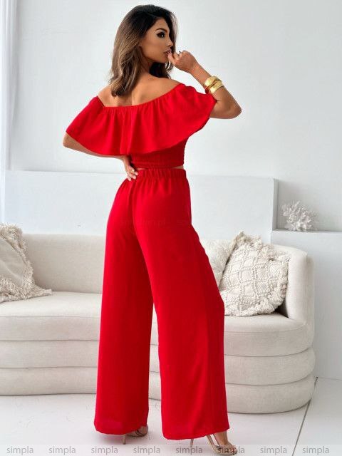 Woman wearing a red jumpsuit in a living room setting