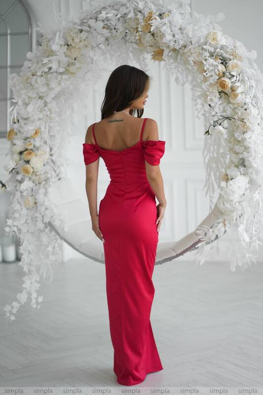 Woman in a red dress standing in front of a floral archway.