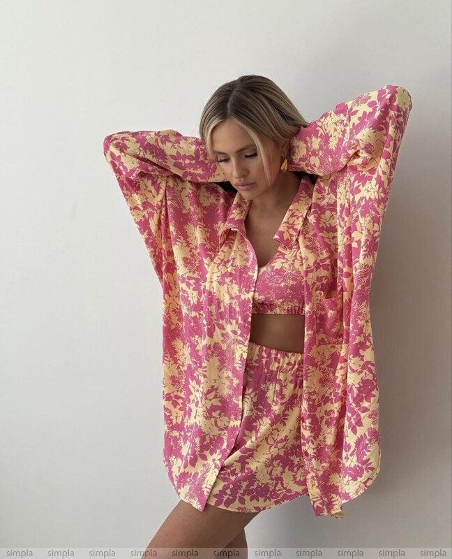 Woman wearing a pink and yellow floral outfit against a plain background