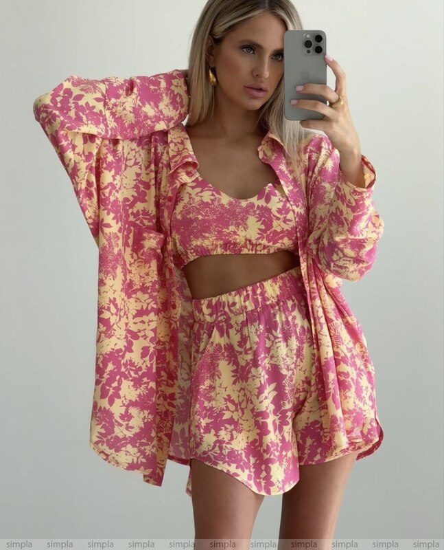 Woman taking a mirror selfie wearing a pink floral outfit on a gray background