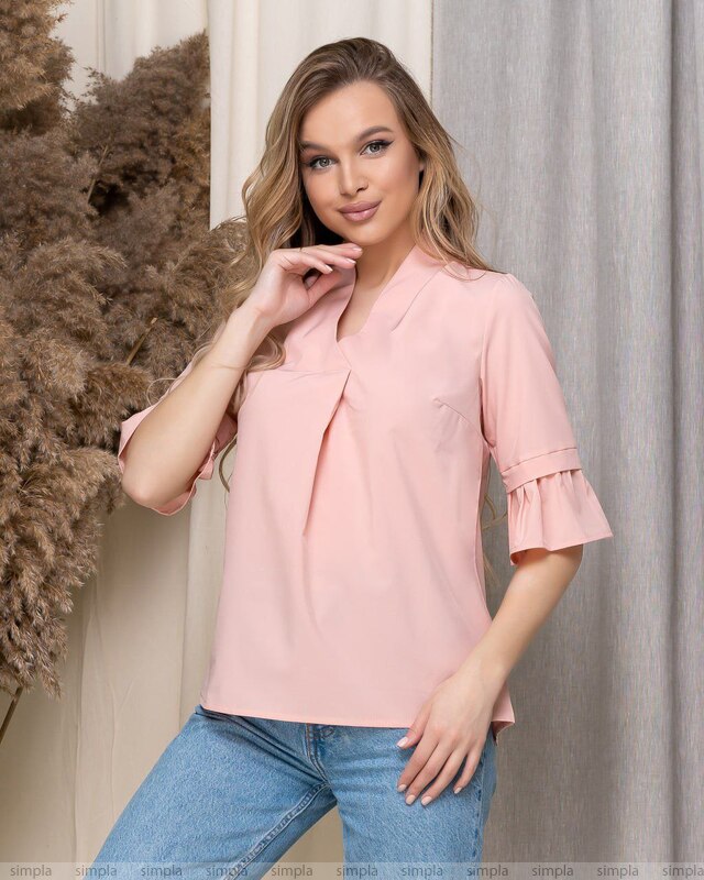 Woman wearing a pink blouse with ruffled sleeves against a neutral background