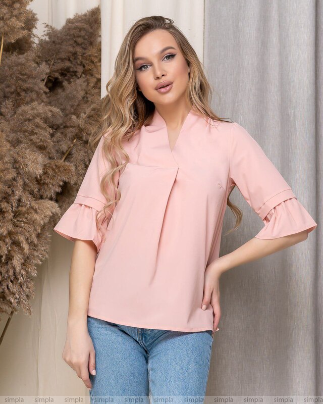 Woman wearing a pink blouse with ruffled sleeves against a neutral background
