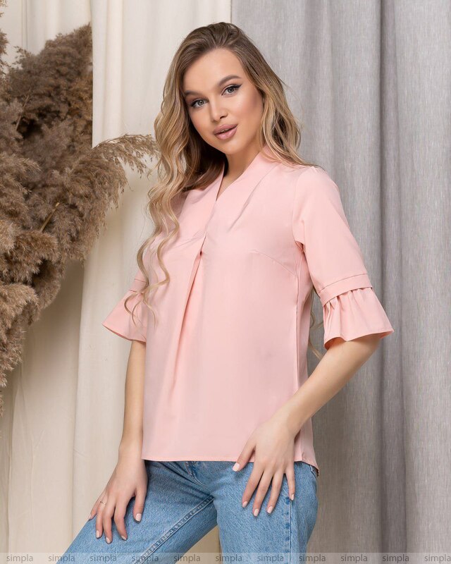 Woman wearing a pink blouse with ruffled sleeves against a neutral background