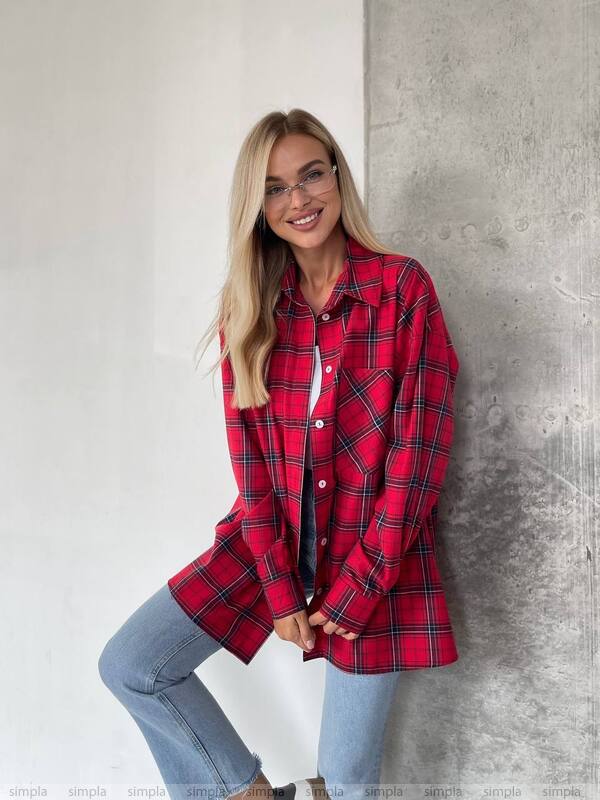 Woman wearing a red plaid shirt against a concrete wall.