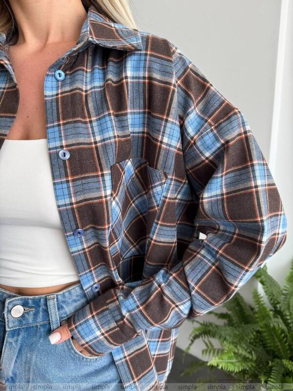 Person wearing a plaid shirt over a white top with a blurred background