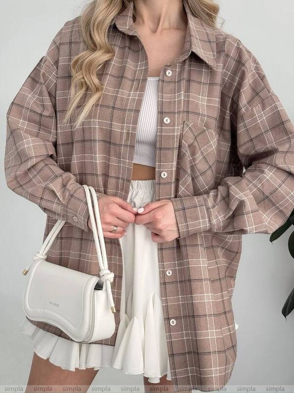 Person wearing a plaid shirt with a white handbag on a plain background