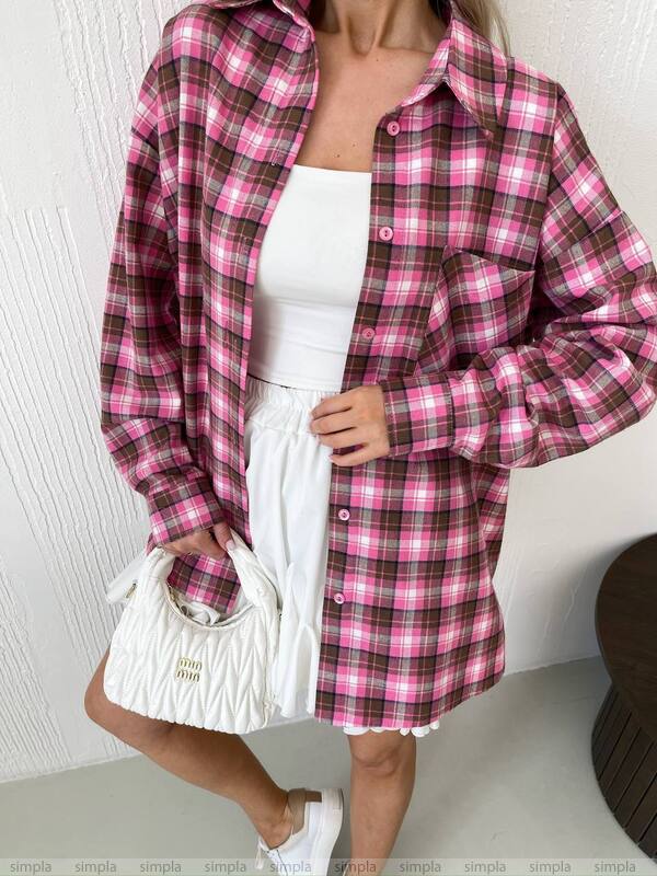 Person wearing a pink and brown plaid shirt over a white top and skirt, holding a white handbag.