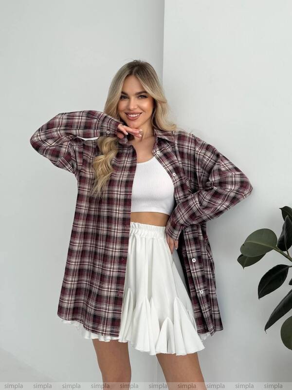Woman wearing a plaid shirt over a white top and skirt against a white background