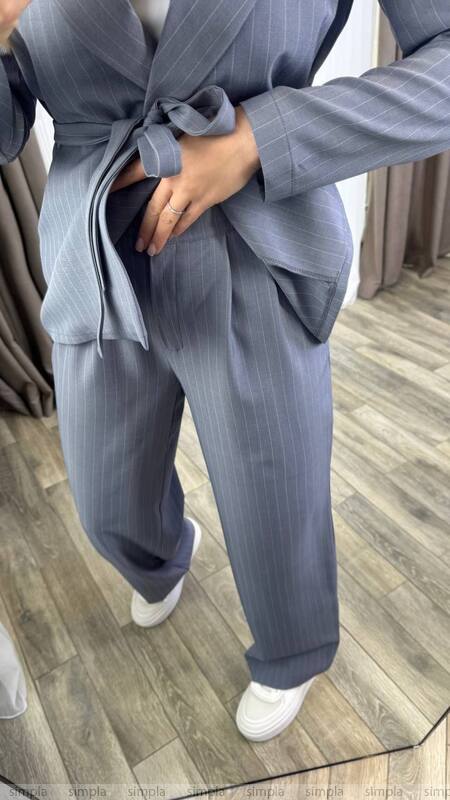 Person wearing a gray pinstripe suit with a matching blazer and pants on a wooden floor.