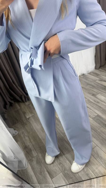 Person wearing a light blue suit standing on a wooden floor.