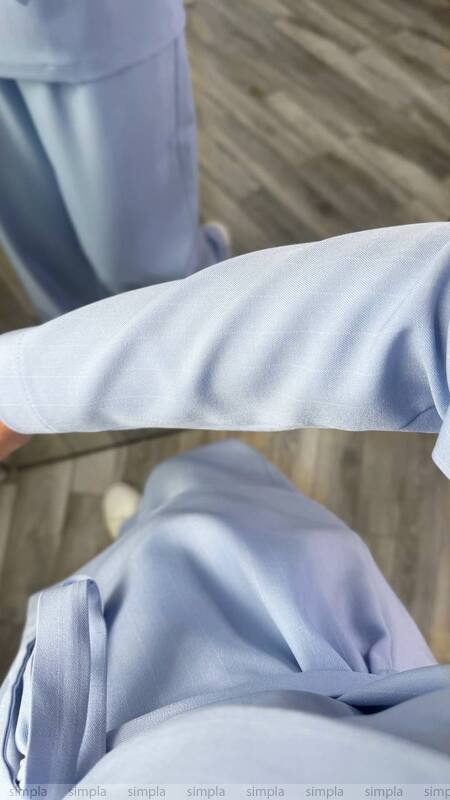 Close-up of light blue pants and shirt on a wooden floor