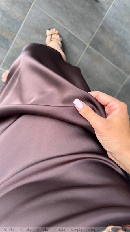 Person holding a piece of brown fabric on a tiled floor