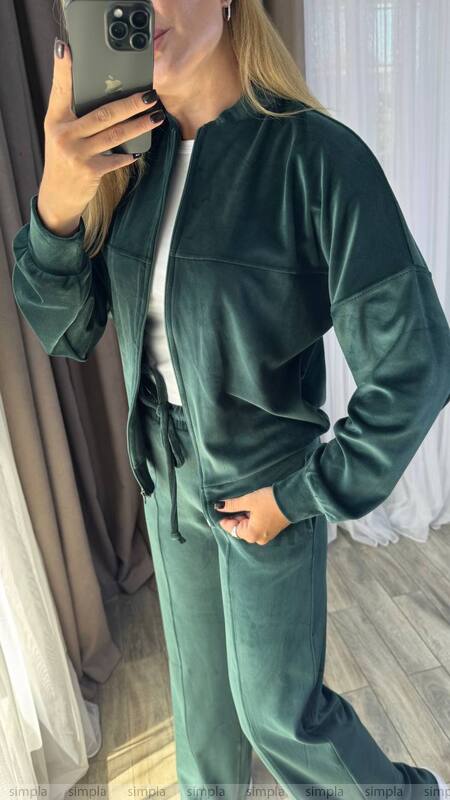 Person wearing a green tracksuit taking a mirror selfie.