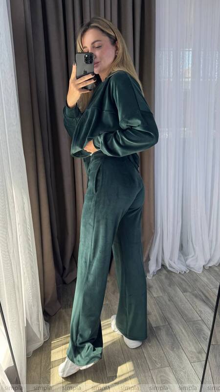 Person wearing a green velvet outfit taking a mirror selfie.