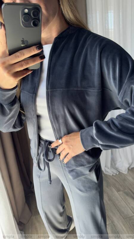 Person wearing a gray tracksuit taking a mirror selfie.