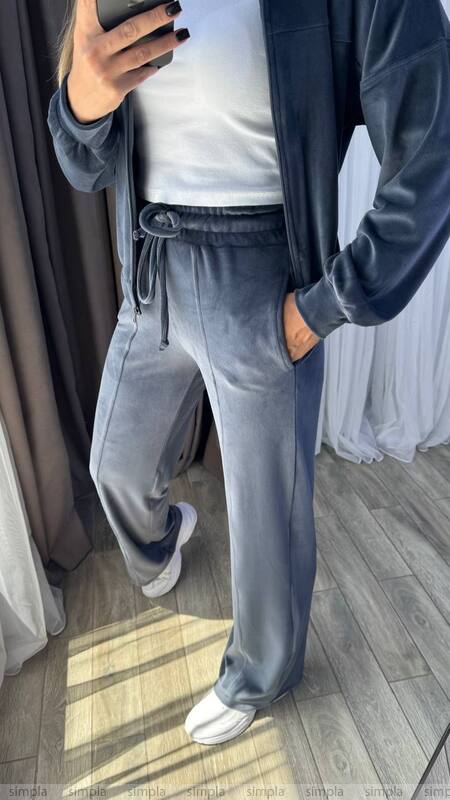 Person wearing a blue tracksuit with white sneakers in a room.