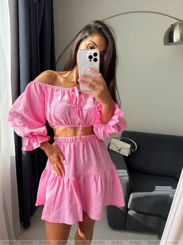 Woman taking a mirror selfie wearing a pink off-shoulder top and skirt set.