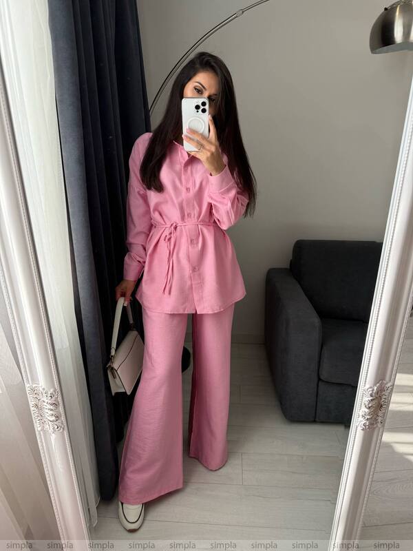 Person wearing a pink outfit taking a mirror selfie in a room.