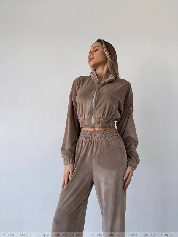 Woman wearing a brown tracksuit against a plain background