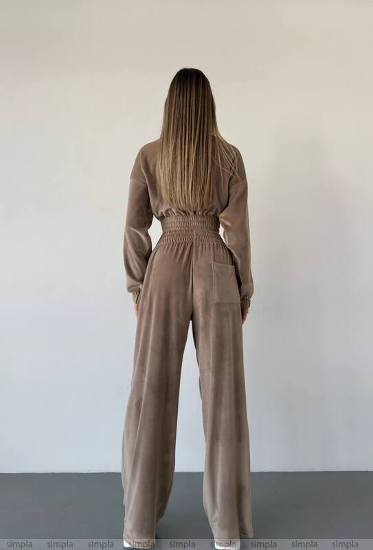 Person wearing a brown jumpsuit against a plain background