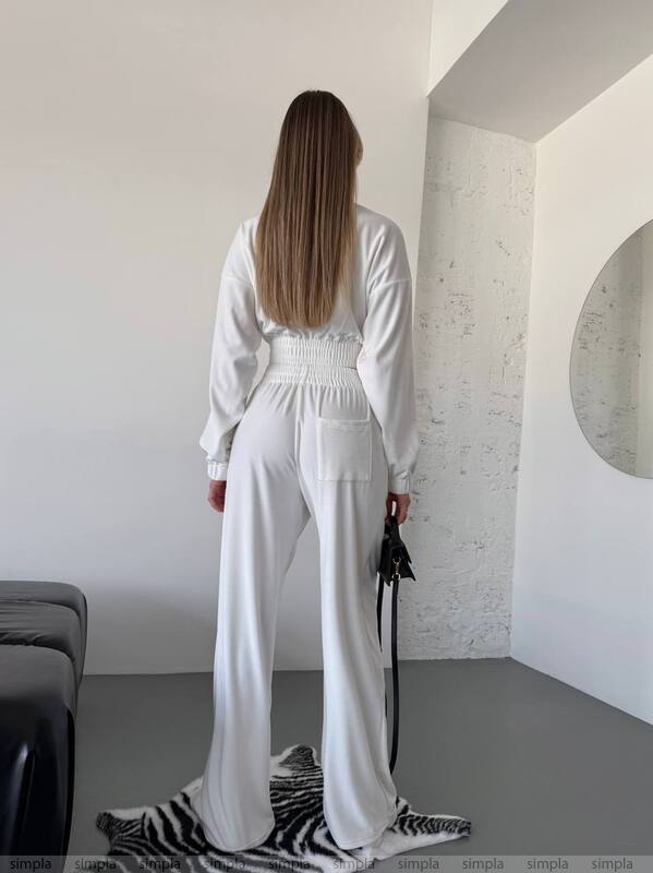 Person wearing a white outfit in a minimalistic room.