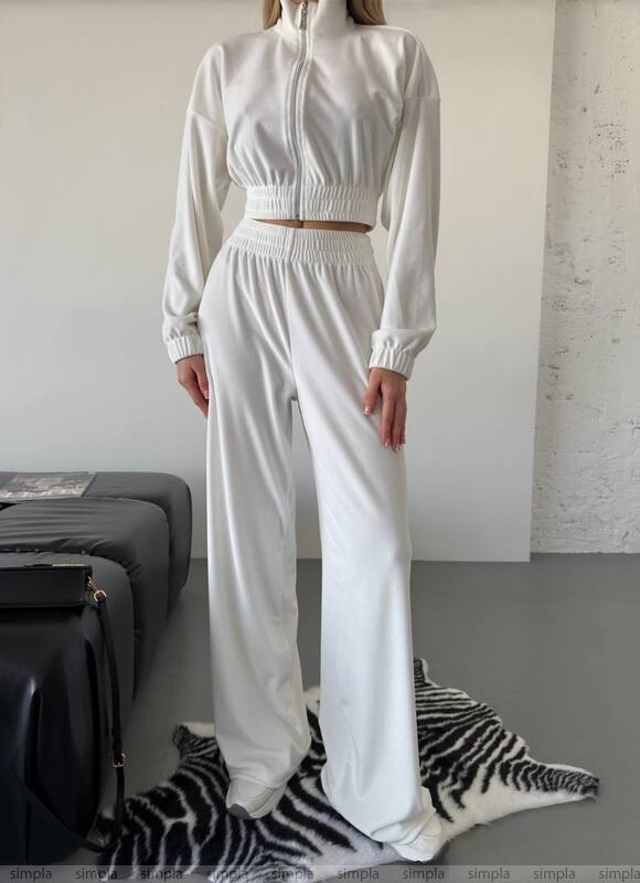 Person wearing a white outfit standing in a minimalistic room with a zebra-patterned rug.
