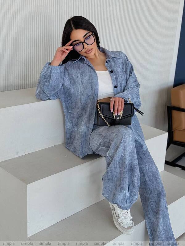 Woman in a blue denim outfit sitting on a white geometric bench.
