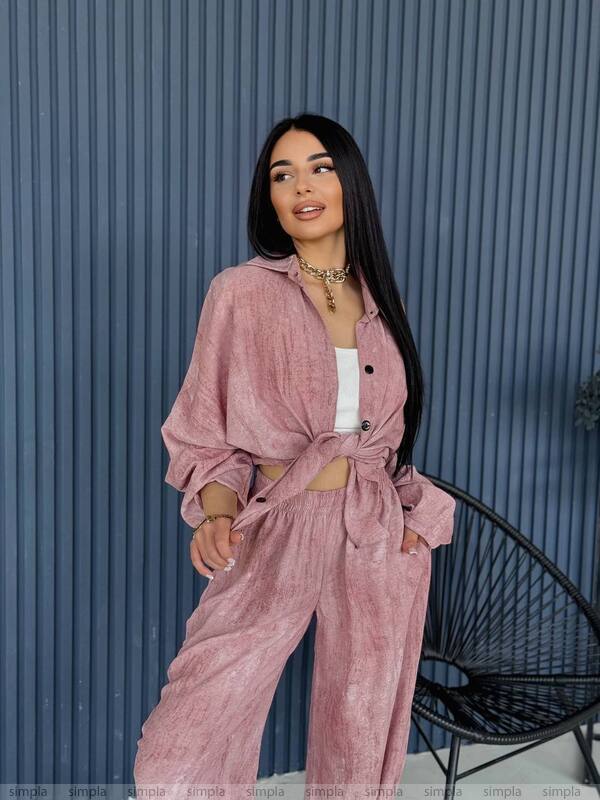 Woman wearing a pink outfit standing against a blue corrugated metal background