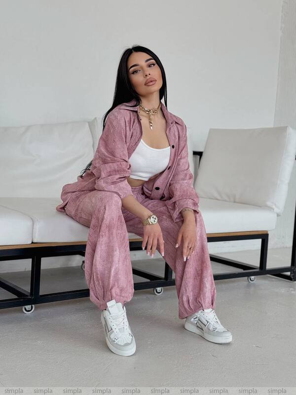 Woman in a pink outfit sitting on a white couch in a minimalistic room.