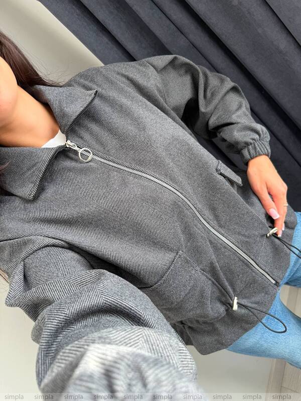 Person wearing a gray zip-up hoodie with a neutral background