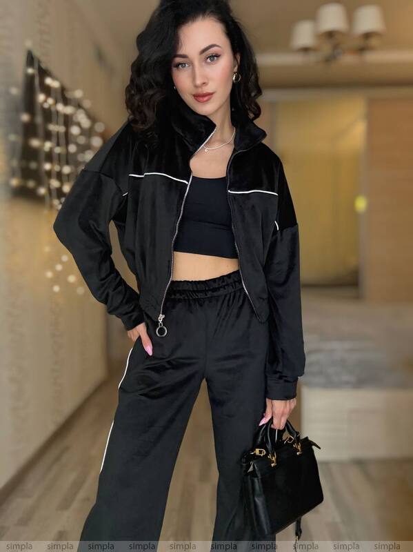 Woman in a black outfit holding a handbag in an indoor setting