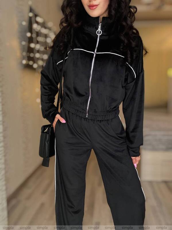 Person wearing a black tracksuit with white accents indoors.