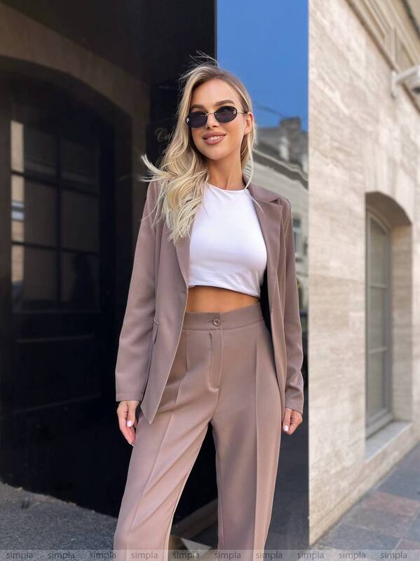 Woman in a stylish outfit standing outdoors with a building in the background
