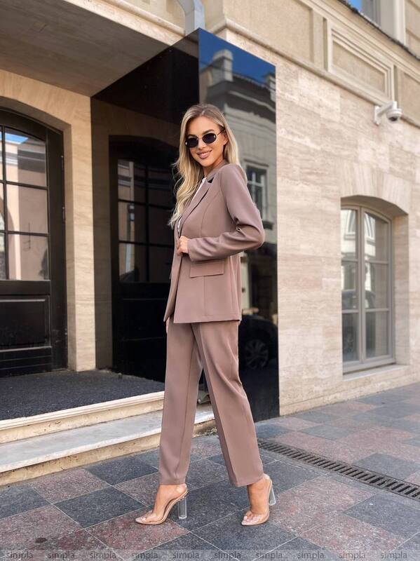 Woman in a beige suit standing outside a building