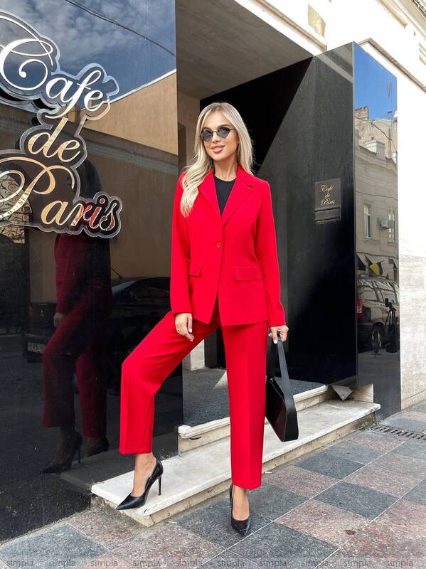 Woman in a red suit standing outside a building with 'Cafe de Paris' sign.