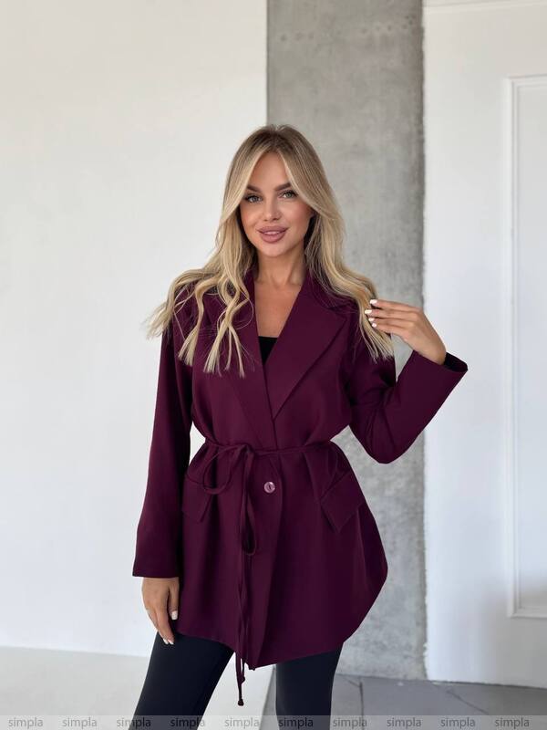 Woman wearing a burgundy coat against a neutral background