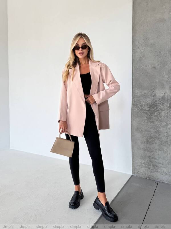 Woman wearing a pink coat, black outfit, and sunglasses indoors.