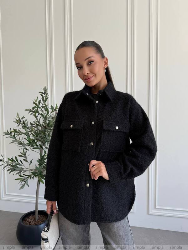Woman wearing a black jacket in a minimal indoor setting