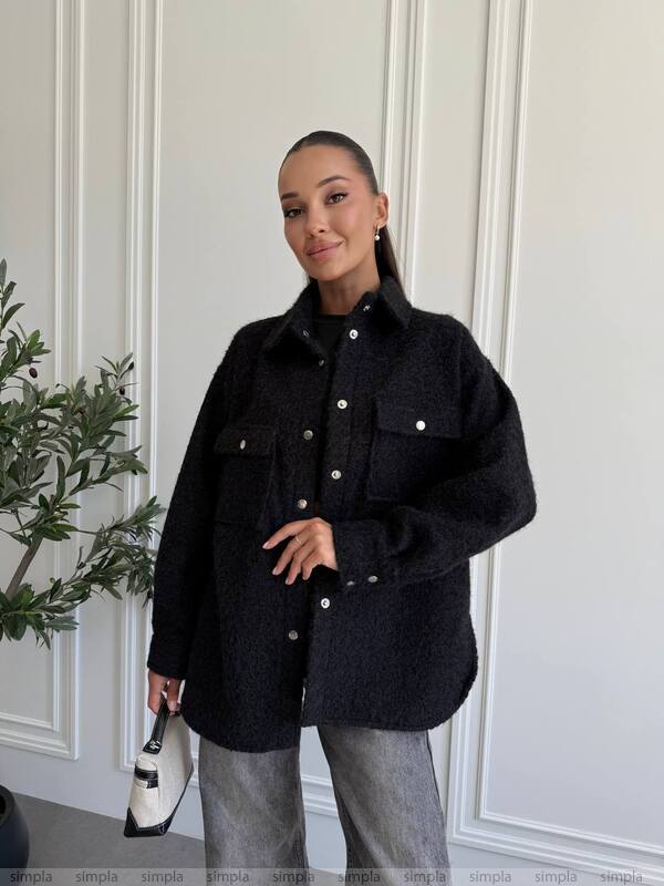 Person wearing a black coat in a minimal indoor setting