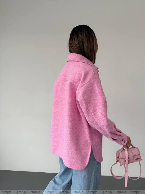 Person wearing a pink coat holding a matching pink handbag against a plain background