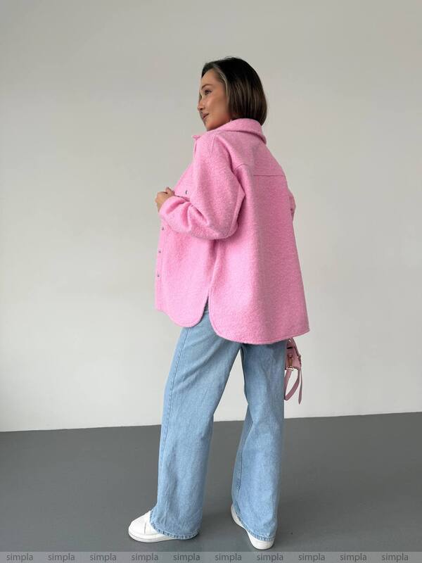 Person wearing a pink coat and blue jeans against a plain background