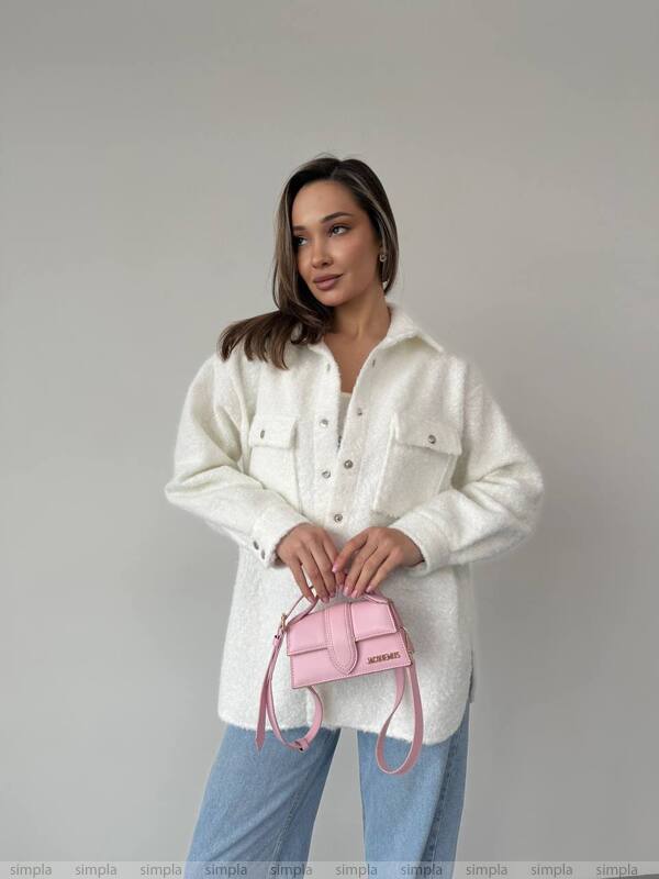Woman holding a pink handbag against a plain background
