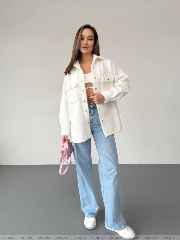 Woman wearing a white jacket, light blue jeans, and white sneakers, holding a pink bag and a coffee cup.