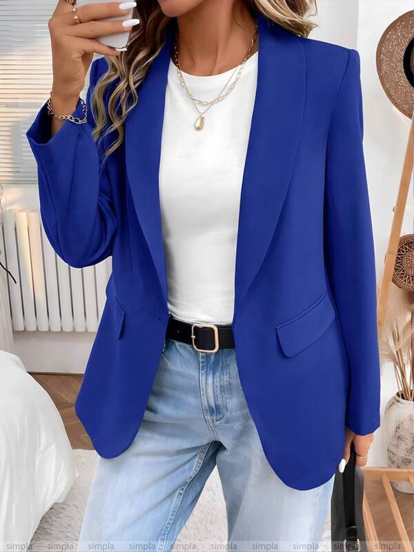 Person wearing a blue blazer, white top, and jeans indoors.